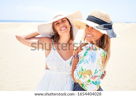 Young beautiful friends on vacation wearing hat and summer clothes smiling happy and confident. Standing with a smile on face at the beach