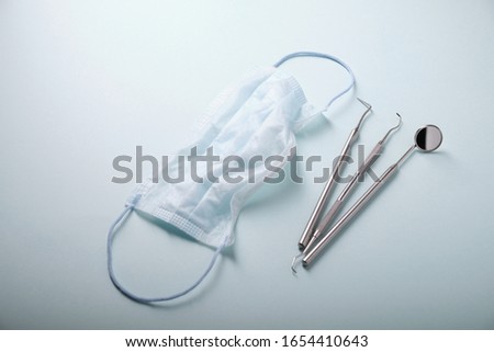 Metal dental tools on a blue background, face mask
