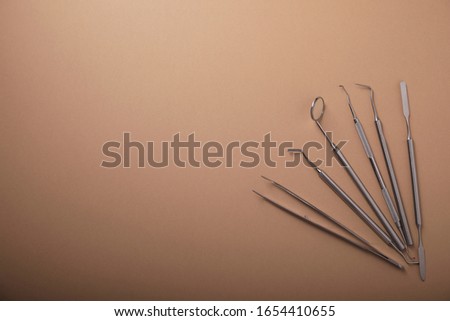 Metal dental tools on an orange background