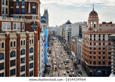 Business shopping area on Gran Via with historical buildings and traffic in Madrid, Spain. Royalty-Free Stock Photo #1654434964