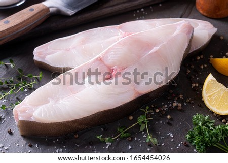 Delicious fresh halibut steaks on slate with lemon and parsley.