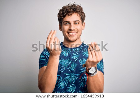 Young blond handsome man on vacation with curly hair wearing casual summer t-shirt doing money gesture with hands, asking for salary payment, millionaire business