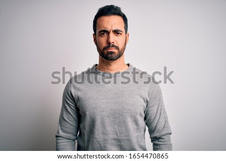 Young handsome man with beard wearing casual sweater standing over white background depressed and worry for distress, crying angry and afraid. Sad expression. Royalty-Free Stock Photo #1654470865
