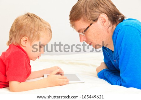 father and son looking at touch pad at home