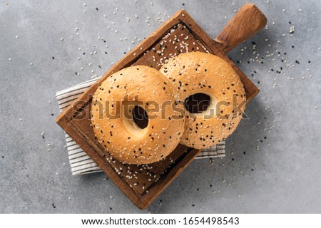 Two sesame bagels on wooden cutting board. Table top view Royalty-Free Stock Photo #1654498543