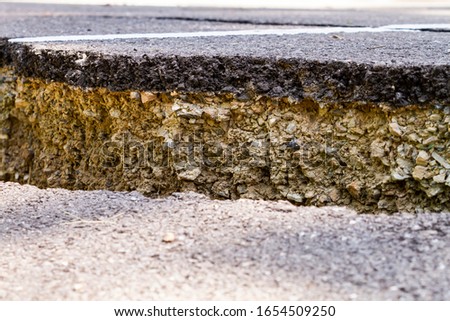 Road surface with cracks in the pavement and soil layers