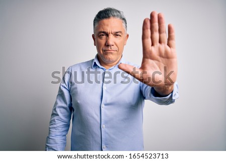 Middle age handsome grey-haired business man wearing elegant shirt over white background doing stop sing with palm of the hand. Warning expression with negative and serious gesture on the face.