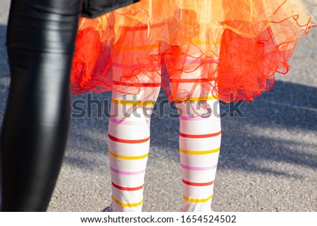 Young girl and parent wearing a colorful costume at a street carnival party