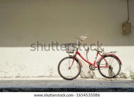 Vintage old city bicycle against white concrete wall for background under summer warm sunlight Royalty-Free Stock Photo #1654535086