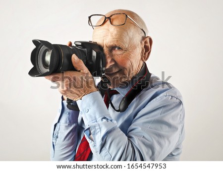 Old man holding a camera like a professional.