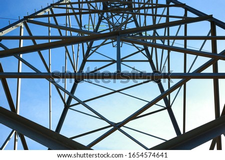 Power transmission tower close-up. Geometric, siluette. Blue sky at the background.