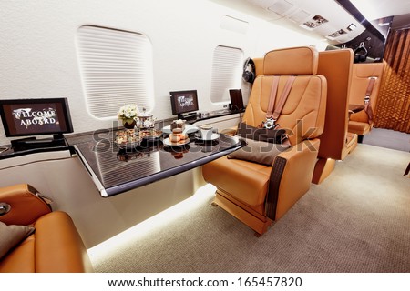 Private plane interior with wooden tables and leather seats Royalty-Free Stock Photo #165457820