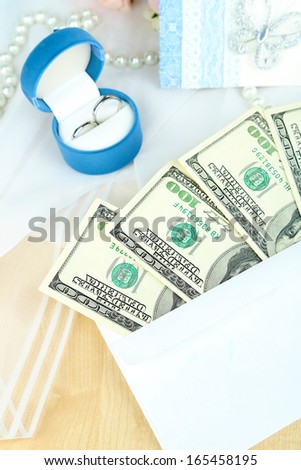 Dollar bills in envelope as gift at wedding on wooden table close-up
