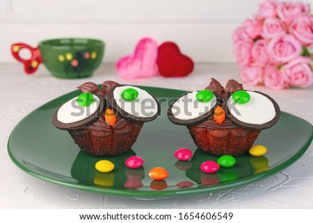 On a white background, chocolate cupcakes-owls, a Cup, hearts and a bouquet of roses. Cute owl dessert. Copy space