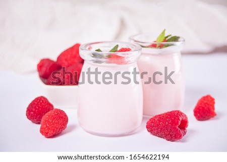 Two portions natural homemade yogurt in a glass jar with fresh raspberry. Breakfast concept