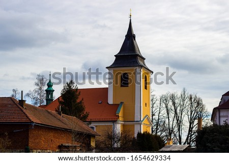 Beautiful medieval Czech church tower behind leafless trees. Czech Republic.