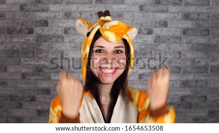 pajamas in the form of a giraffe. emotional portrait of a woman on a gray brick background . crazy and funny man in a suit. animator for children's parties. Halloween party costume