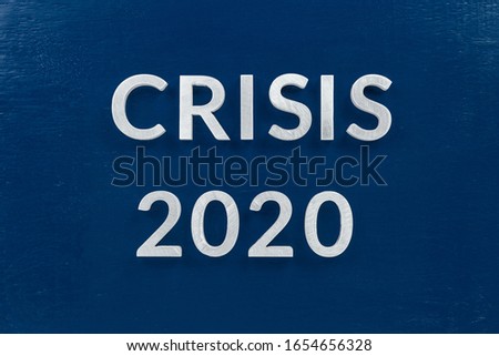 the words crisis 2020 laid with silver metal letters on blue surface for stock market background