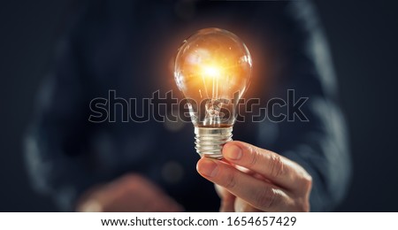Creative new idea. Innovation, brainstorming, inspiration and solution concepts. The man is holding light bulb. Copy space background. Royalty-Free Stock Photo #1654657429