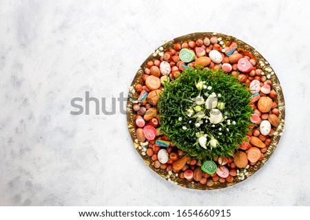 Traditional Azerbaijan holiday Novruz background with xoncha,green semeni,traditional azerbaijan sweets,shekerbura,qogal,paxlava,mutaki and different nuts and sweets,top view,space for copy