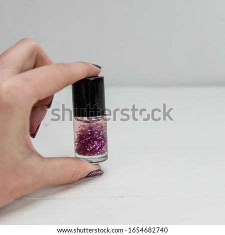 Hand holding glittery colorful and bright nail polish isolated with copy space.