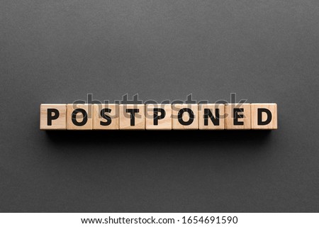 Postponed - words from wooden blocks with letters, postponed concept, top view gray background Royalty-Free Stock Photo #1654691590