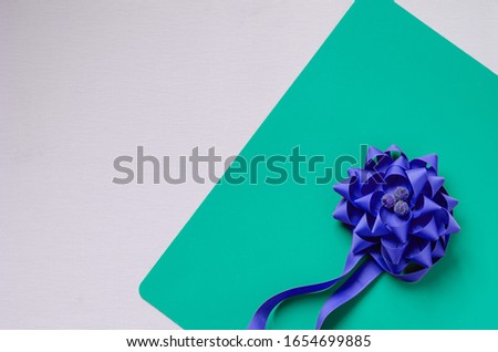 Blue Decorative Flower woven from a ribbon. Composition on a textured background. Top view at an angle. Selective focus. Multitask background.