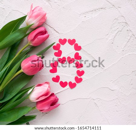 Beautiful spring tulips and hearts in the shape of eight on grey stone background. Concept of Women's Day March eight.