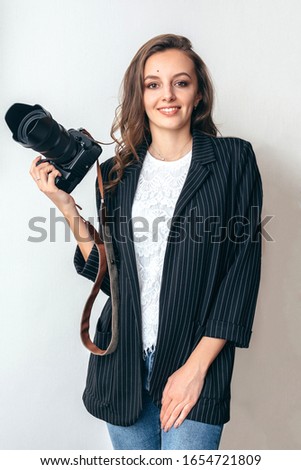 Girl in a jacket with a camera on a white background.