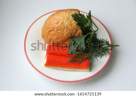 Still life of a piece of white bread, crab sticks and parsley on a white plate with a red border. Stock photo for web and print, walpaper and background. 