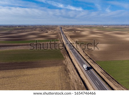 Truck on road in Vojvodina,Serbia. New road near city of Subotica. Lorry moving on road. Cargo transportation background. Aerial view at truck driving between fields. Royalty-Free Stock Photo #1654746466