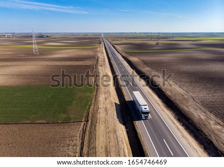 Truck on road in Vojvodina,Serbia. New road near city of Subotica. Lorry moving on road. Cargo transportation background. Aerial view at truck driving between fields. Royalty-Free Stock Photo #1654746469