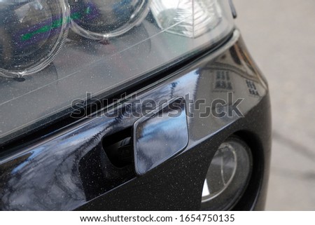 Headlight washer system of the black car. The headlight washer is broken, not working. Breakdown of the car's washing system