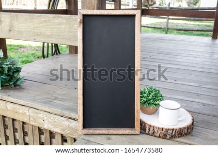 Blank vertical chalkboard wood sign on garden deck, rustic camping sign mockup