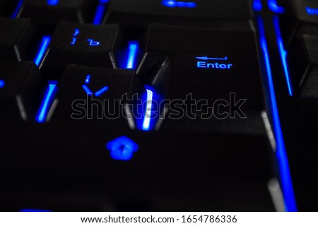 Abstract background of black computer keyboard with blue backlight. Closeup photo with bokeh, can be used like a wallpaper.