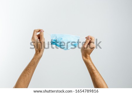 Female hand holds blue surgical mask with rubber ear straps. Typical three-layer surgical mask for covering the mouth and nose. Protection concept
