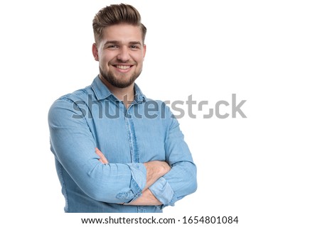 Happy casual man smiling and holding his hand crossed at his chest, standing on white studio background