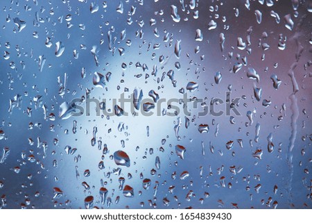 rain droplets on glass over calm colorful background. business backdrop.