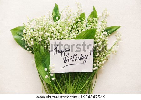 Happy birthday card with greeting words and bouquet of white lily of the valley flowers