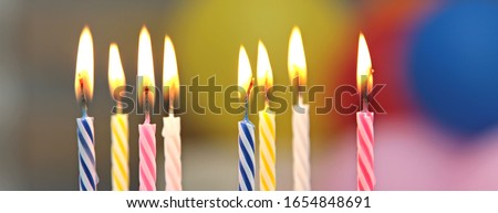 Birthday candles and colorful blurred background.