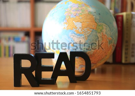 Picture of the English alphabet on the table in the library Bookshelf and globe in the background selective focus and shallow depth of field