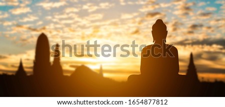 Silhouette of Buddha on golden temple sunset background. Travel attraction in Thailand.