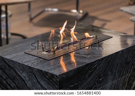 Beautiful marble black floor fireplace. Minimalism interior, alternative bio fireplot fireplace on ethanol gas.