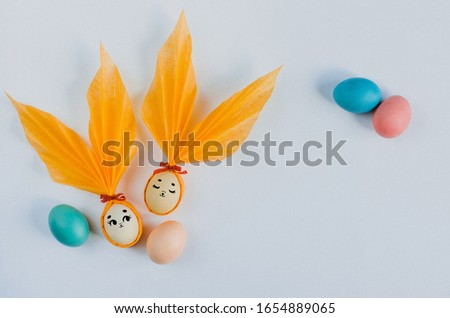Easter Bunnies made of eggs with yellow ears, with cute painted eyes. Eggs painted in different colors. White background in middle of compositions for your Happy Easter greetings text or invitation.