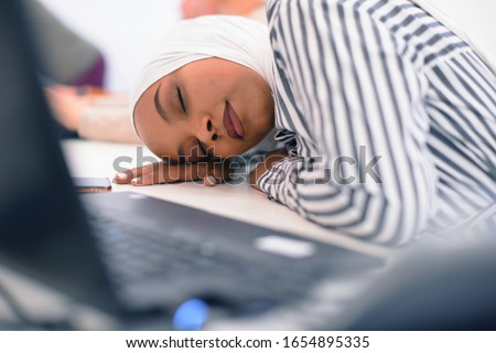 African business muslim woman sitting at her desk and sleeping isolated on white background