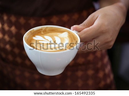 woman holding hot cup of coffee,with leaf