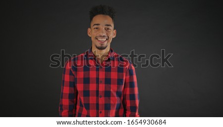 Calm african man in shirt standing isolated on dark background and looking on camera