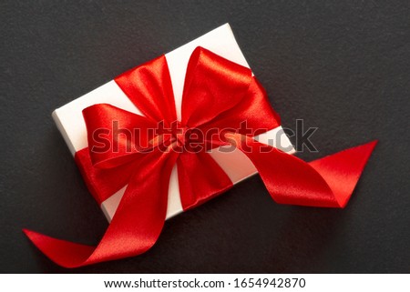 Gift white box with a red bow on a dark background. Valentine's Day, Christmas, Birthday, Mother's Day.
