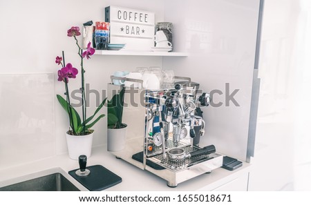 Home kitchen decor coffee bar for espresso machine on countertop, modern apartment living, wall shelves, orchid flower, indoor lifestyle.