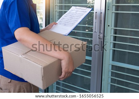 Delivery man in blue uniform handing parcel box for client  signing checklist after confirm receiving package 